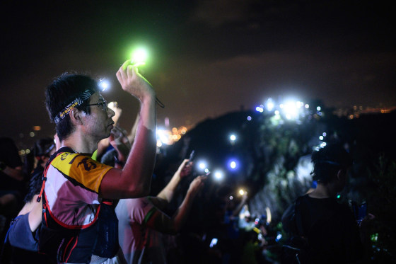 Image: A protester lights up a laser beam at the hill top of Lion Rock in Hong Kong