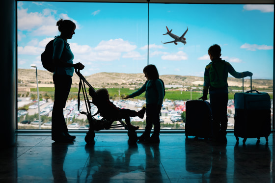 Image: mother with kids and luggage looking at planes in airport