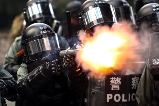 Image: A riot police fires tear gas to disperse anti-government protesters after a march in Hong Kong