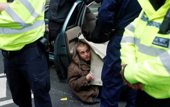 Image: Police officers remove a protester attached to a car during Extinction Rebellion protesters demonstrate in Westminster, London