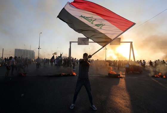 Image: An Iraqi protester waves the national flag during a demonstration against state corruption, failing public services, and unemployment, in the Iraqi capital Baghdad