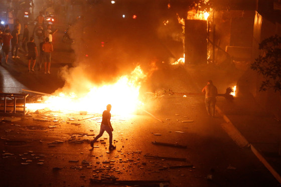 Image: A demonstrator walks close to a fire during a protest over deteriorating economic situation in Beirut