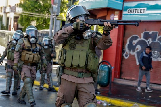 Image: A riot policeman shoots at demonstrators during protests in Valparaiso, Chile