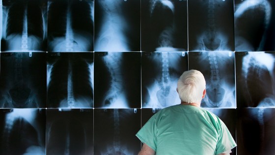 Senior doctor looking at x-rays, rear view