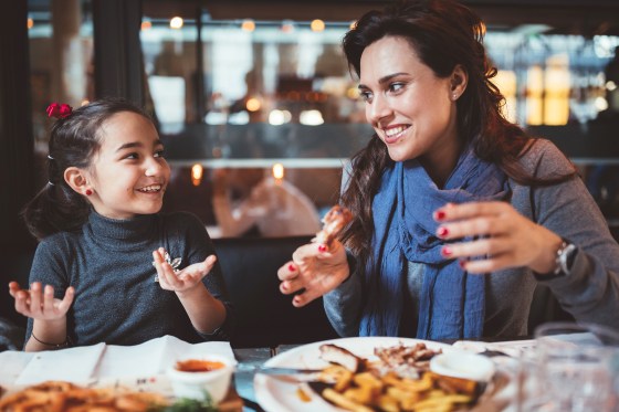 Image: Mother with little daughter eating dinner in restaurant