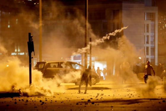 Image: Demonstrators hurl tear-gas canisters back at riot police in Beirut, Lebanon, on Dec. 14, 2019.