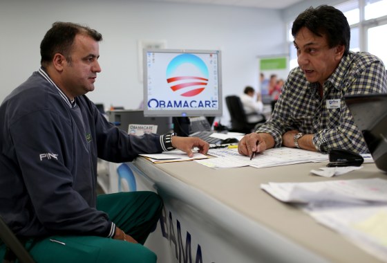 Image: Ariel Fernandez, left, sits with Noel Nogues, an insurance adviser, as he signs <a href=