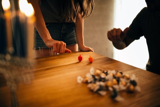Man and woman with menorah playing dreidel game on Hannukah
