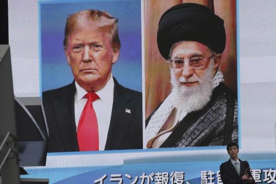 Image: A man walks by a huge screen showing U.S. President Donald Trump, left, and Iranian Supreme Leader Ayatollah Ali Khamenei, in Tokyo