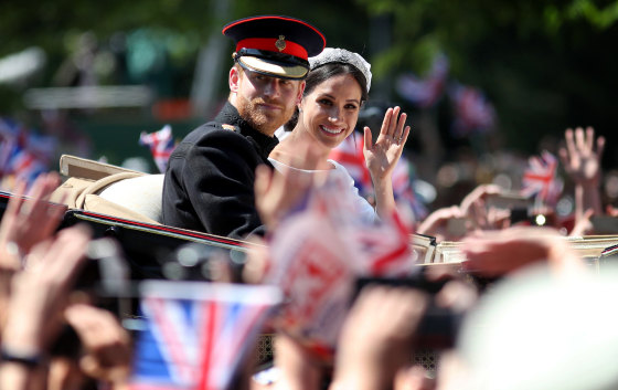 Image: Prince Harry and Meghan, Duchess of Sussex, wave from their carriage during a procession after their wedding ceremony in Windsor on May 19, 2018.