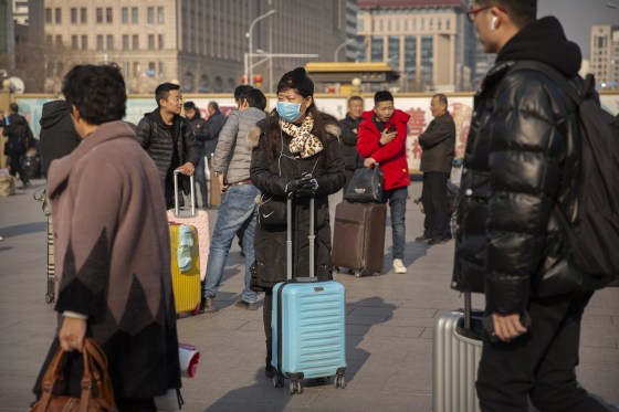 Image: A traveler wears a facemask as she stands near the Beijing Railway Station in Beijing,