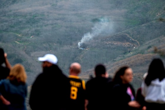 Image: People watch as smoke rises from the scene of a helicopter crash that killed basketball star Kobe Bryant in Calabasas, Calif., on Jan. 26, 2020.