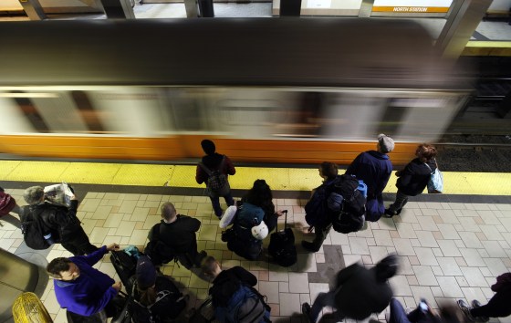 Commuters at the North Station T station in Boston wait as an Orange Line train pulls in