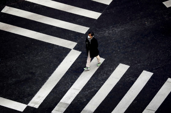 Image: A man wearing a protective mask crosses the street in Seoul on Feb. 20, 2020.