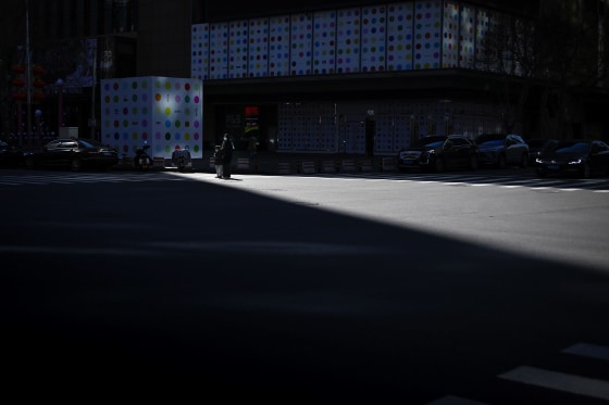 Image: A woman and a child wearing face masks wait to cross a street in Beijing