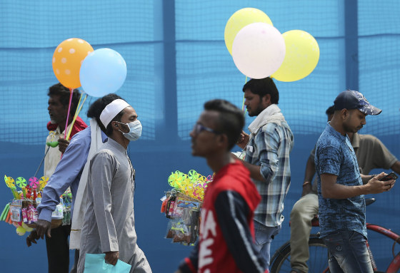 Image: An Indian wears a mask and walks on a street in Hyderabad