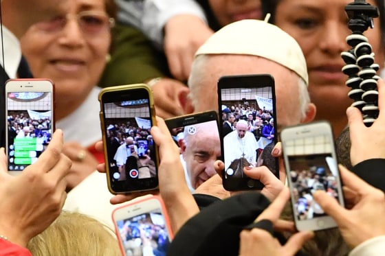 The faithful take photos of Pope Francis with their mobile phone at the Vatican