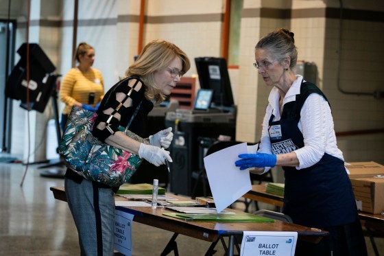 Image: An election worker assists a voter during the Florida primary in Miami