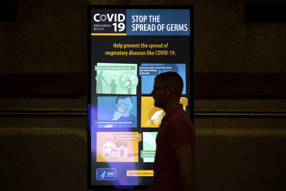Image: A commuter walks past a CDC display of coronavirus information at the Gallery Place Metro station in Washington on March 13, 2020.