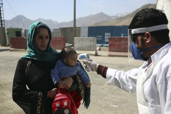 Image: An Afghan health worker measures the temperature of Afghan passengers in an effort to prevent the spread of the coronavirus, as they enter Kabul trough Kabul's western entrance gate, in the Paghman district of Kabul
