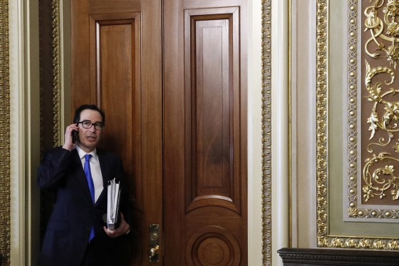 Image: Treasury Secretary Steve Mnuchin speaks on a phone after stepping out of a meeting on Capitol Hill