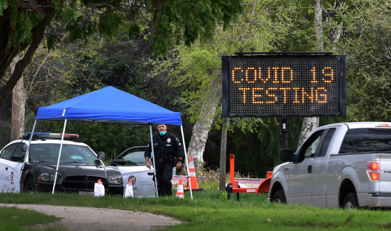 Image: A police officer mans the entrance to a coronavirus (COVID-19) testing center in Hansen Dam Park on March 25, 2020 in Pacoima, California.