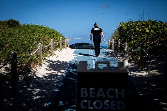 Image: A police officer walks toward a closed portion of South Beach, Fla., on March 19, 2020.