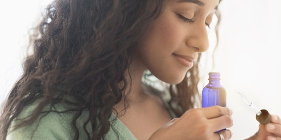 Close up of mixed race woman smelling aromatherapy oil