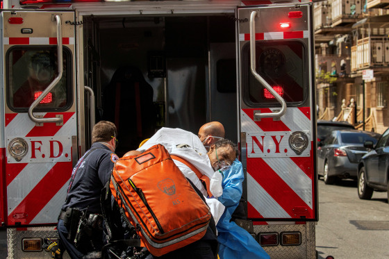 Image: New York City Fire Department and Emergency Medical Technicians lift a man after moving him from a nursing home into an ambulance