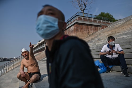 Image: A man wears a face mask as people gather along the Yangtze river in Wuhan, China's central Hubei province