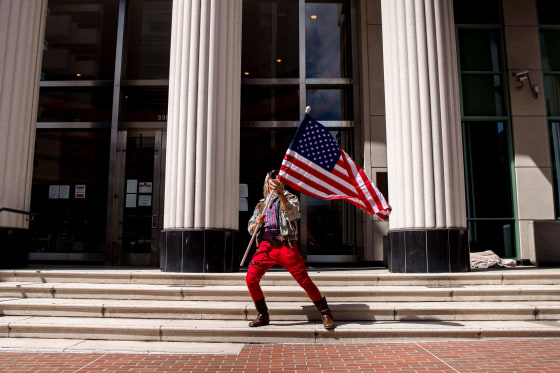 Image: A man waves an American flag during a rally against California's stay at home orders in San Diego on April 18, 2020.