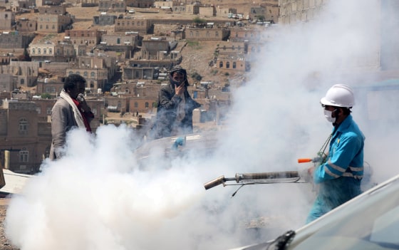 Image: People cover their faces as a health worker fumigates a residential area in the battle against the coronavirus outbreak on the outskirts of Sanaa, Yemen