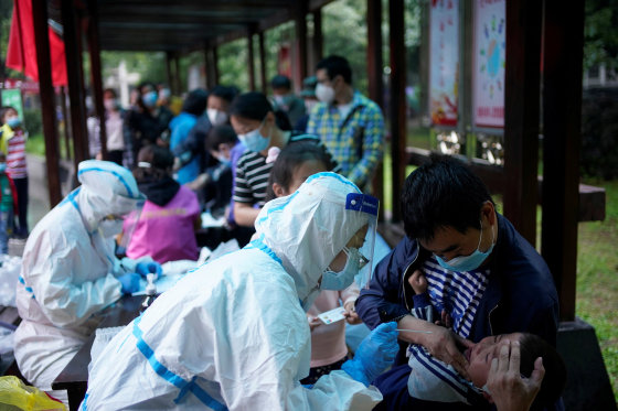 Image: A medical worker in a protective suit conducts a nucleic acid testing for a child at a residential compound in Wuhan, the Chinese city hit hardest by the coronavirus disease (COVID-19) outbreak, Hubei province