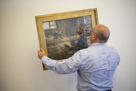 Image: Meir Heller, the Jerusalem lawyer holds Max Liebermann's \"Basket Weavers\" painting in a law office in Jerusalem,