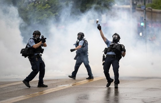 Image: A police officer throws a tear gas canister towards protesters at the Minneapolis 3rd Police Precinct, following a rally for George Floyd