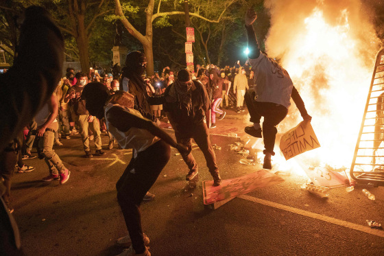 Image: Protesters jump on a street sign near a burning barricade during a demonstration against the death of George Floyd near the White House