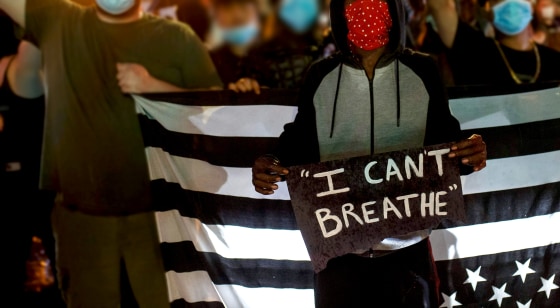 People hold up their fists after protesting near the spot where George Floyd died while in custody of the Minneapolis Police, on May 26, 2020 in Minneapolis