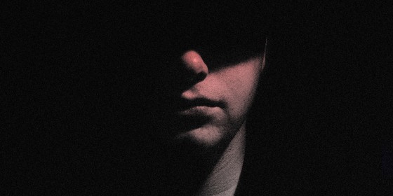 Image: Portrait of a man with half of his face hidden in shadow.