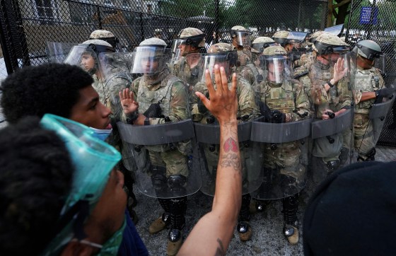 Image: At sunrise, a protester waves goodbye at soldiers withdraw in Washington