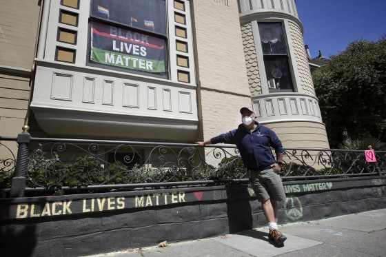 Image: James Juanillo stands next to a chalk message outside of his home in San Francisco on June 14, 2020.