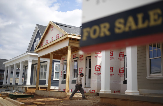 A contractor walks past a \"For Sale\" sign while working on a home in Louisville, Ky.