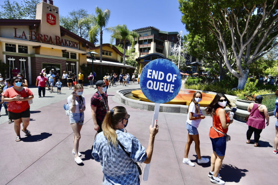 A Disney employee runs a line to get in to the virtual queue for the World of Disney on the reopening day of the Downtown Disney District in Anaheim, Calif., on July 9, 2020.