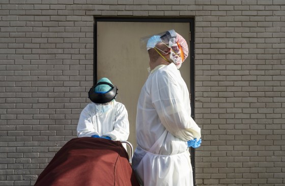Image: Medical staff wait for a car to pick up a deceased patient outside of the COVID-19 intensive care unit