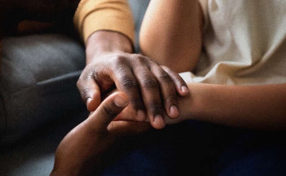 Image: A Black man holds the hand of a child