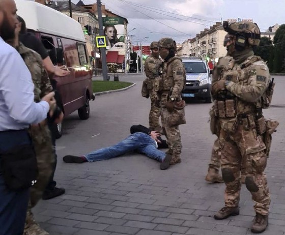 Image: An assailant, who seized a long-distance bus with 10 hostages, lies on the ground after police officers captured him in the city centre of Lutsk,