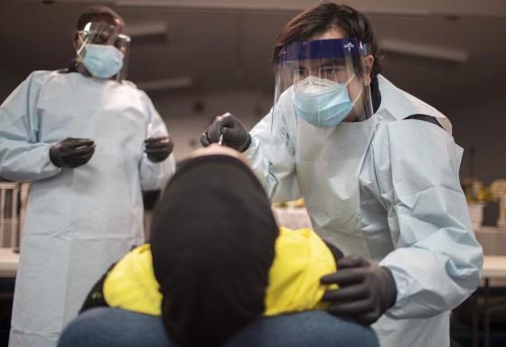 Health care workers use a nasal swab to test a person for COVID-19 at a pop up testing site in Pembroke Park, Fla., on July 22, 2020.