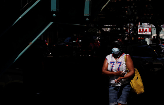Image: A woman wearing a protective face mask walks in the Brighton Beach section of the Brooklyn,