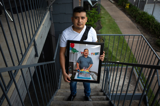 Cristobal Onofre holds up a framed photo of his father, who died from COVID-19 earlier this month, outside his home in Houston.