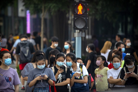 Image: People wearing face masks to protect against the coronavirus wait to cross an intersection in Beijing