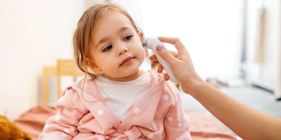 Little girl getting temperature taken with ear thermometer